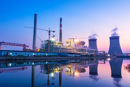 在蓝色和粉红色的日落前，一个平静的水域的发电厂。＂height=
