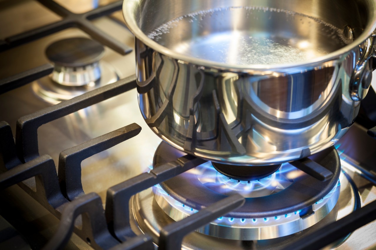 炉子上的煤气燃烧器，不锈钢表面的火焰显示出烹饪食物的热量。不锈钢偷锅上的炉灶烹饪食物。＂class=