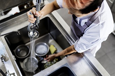 厨房员工在水槽洗餐具的俯视图;Adobe股票:178066106＂class=