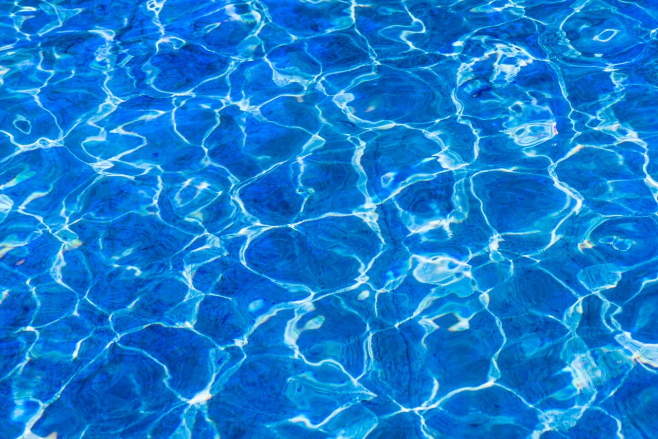 清澈干净的水。近距离观察新鲜，干净，清澈和凉爽的水。暑假邀请。蓝色和白色，光、影和反射的游戏
