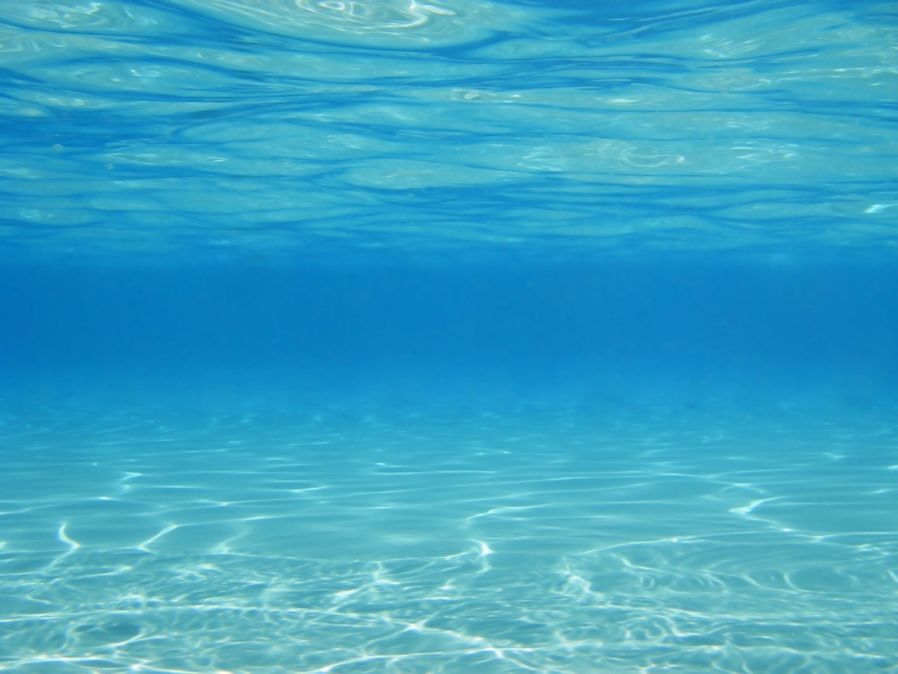 阳光反射在水下游泳池浅深蓝色